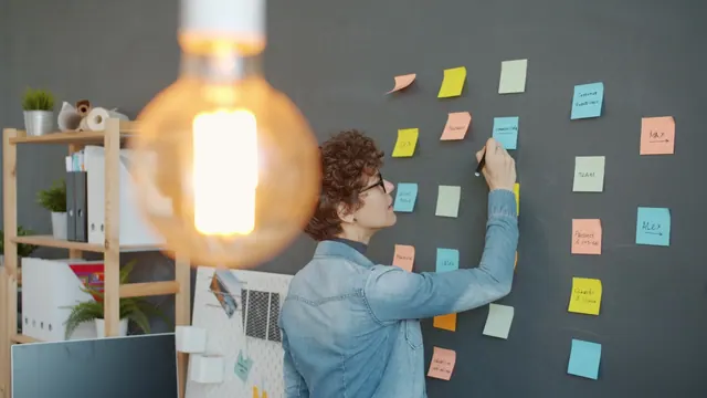 Person writing on colorful sticky notes on wall Creative employee is working at project in office writing on colorful sticky notes on blackboard wall concentrated on business activ. Home-based ideas examples worth studying before you start