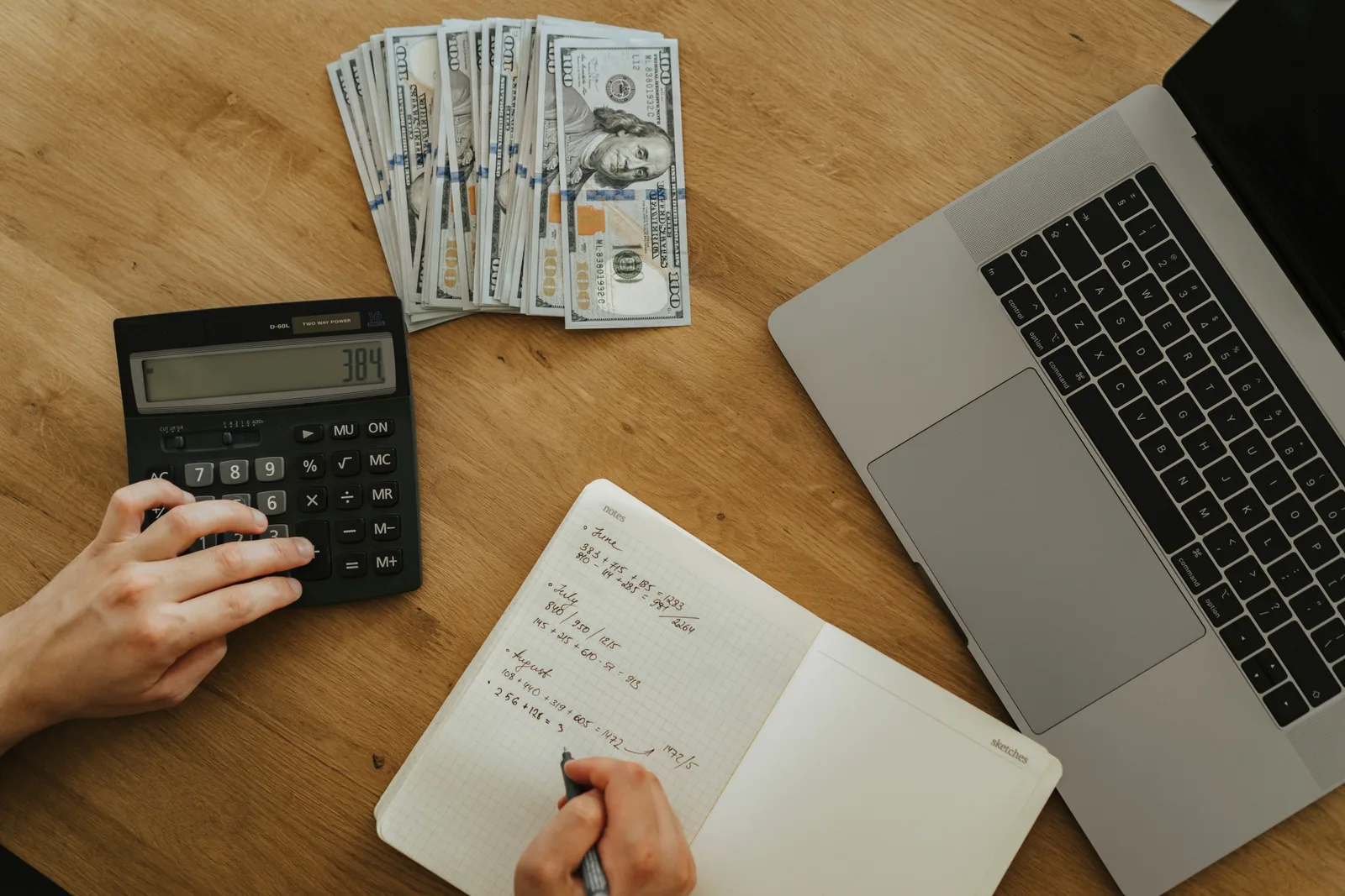 Hands using calculator and notebook, planning finances, with cash and laptop on wooden table. Ideas by skill mistakes worth avoiding early