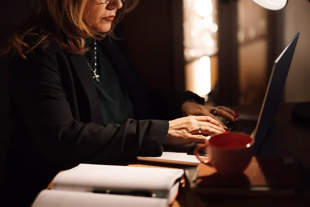 A woman is focused on her laptop while typing in her home office. She has a cup of coffee and some notebooks on the desk. The light is dim, creating a cozy workspace. Ideas for women metrics worth tracking, and the ones to ignore